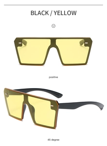 Detail view of oversized square rimless sunglasses in black frame with yellow tinted lenses
