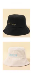 Detailed close-up of peacey letter embroidery on black and beige cotton bucket hats