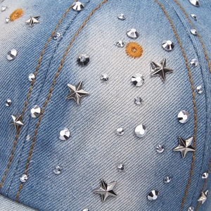 Detail of light blue denim cap featuring silver stars and rhinestone embellishments