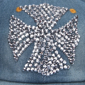 Detailed macro view of sparkling rhinestone cross pattern on blue denim baseball cap