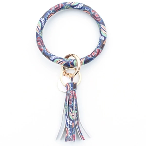 Detail of paisley PU leather bracelet keychain with gold metal rings and fringe tassel