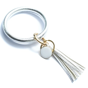 Close-up of silver PU leather bracelet keychain with fringe tassel and white charm