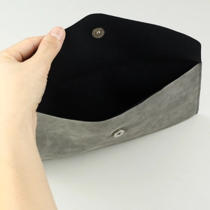 Detail of the magnetic snap closure on a grey faux suede makeup brush envelope bag