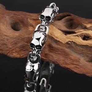 Silver skull head chain bracelet in punk style on dark wood surface for men