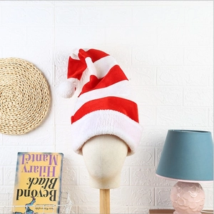 Detail of red and white striped Christmas elf hat with soft plush pompom on a display stand