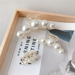 Three sizes of elegant pearl hair claws in a wooden tray showing glossy white pearl details