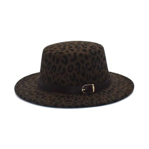 Detail of leopard print flat top wool hat featuring a brown leather band and gold buckle