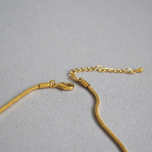 Detailed macro view of the gold snake chain necklace featuring a secure lobster clasp