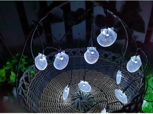 Detail of shell-shaped LED string lights with cold white glow on a woven basket