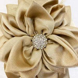 Close-up of a champagne gold satin flower with sparkling rhinestones for evening bags