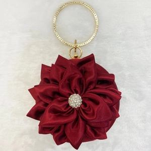 Detail of burgundy silk flower evening bag with rhinestone center and gold metal handle