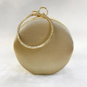 Detailed macro view of champagne silk evening bag with sparkling rhinestone encrusted handle