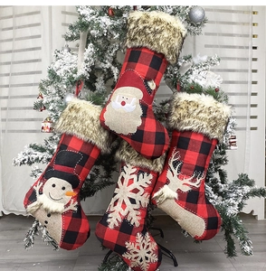 Detail of buffalo plaid Christmas stockings with faux fur trim hanging on a snowy tree
