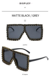 Detail view of matte black oversized sunglasses with crystals and grey lenses