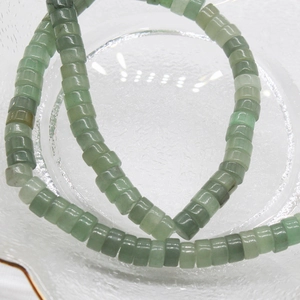 Close-up of 6x3mm green aventurine square abacus beads in a clear glass container