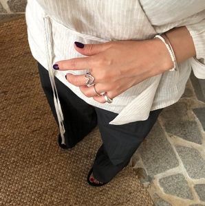 Close-up of knotted heart and minimalist 925 silver rings worn on hand with beaded bracelet