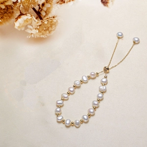 Elegant adjustable freshwater pearl bracelet with gold metal beads on beige fabric