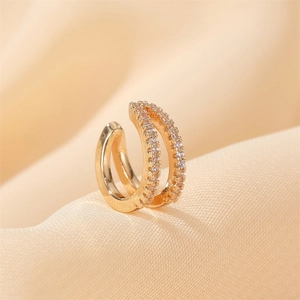 Macro shot of double-layer gold ear cuff with white zircon stones on silk fabric
