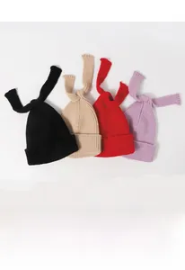Detailed view of knitted winter hats in black, beige, red and purple with long top bows