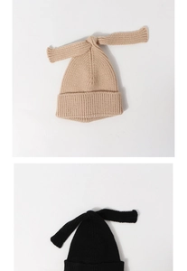 Close-up of beige and black knit baby hats featuring long rabbit ear bow details