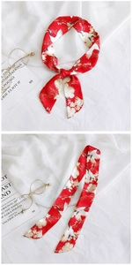 Detail of red silk scarf with crane floral pattern tied elegantly on a book background