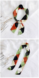 Macro detail of geometric print silk scarf tied on white fabric with artistic accessories
