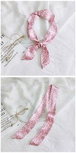 Detail of pink floral silk twilly scarf used as a decorative accessory for handbag handles