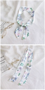 Detail of floral silk twilly scarf with pink flowers and green leaves on white fabric