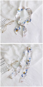 Close-up of white floral twilly scarf tied in a bow with elegant blue and yellow patterns