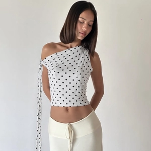 Detailed view of white polka dot one-shoulder top with elegant ribbon tie detail