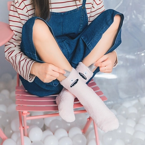 Cozy pink monster cartoon coral fleece crew socks worn by model in a playful setting