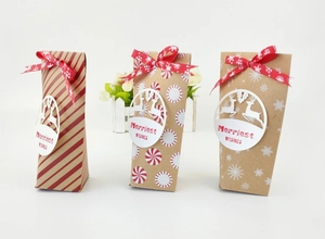 Trois boîtes cadeaux de Noël en papier kraft avec rubans rouges et étiquettes cerf