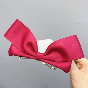 Macro shot of dark red grosgrain ribbon bow hairpin with silver metal spring clip detail