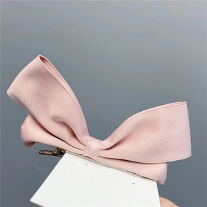 Detailed view of pink ribbon bow hair clip with metal alligator grip on display card