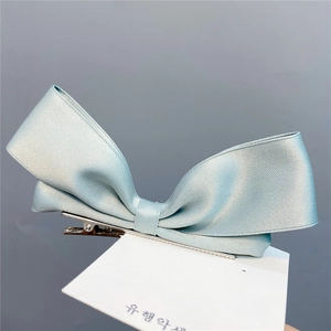 Detailed view of mint green satin bow hair clip with elegant double-layered ribbon design