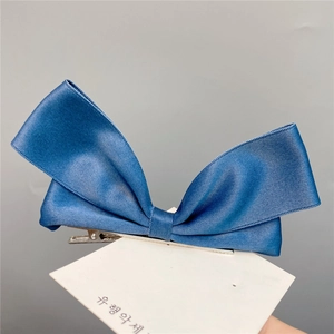 Detail of blue satin bow hair clip with silver metal alligator clip on display card