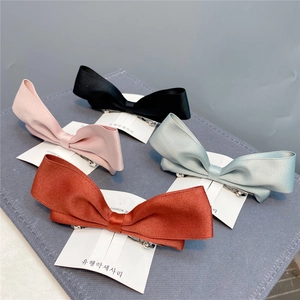 Four colorful satin ribbon bow hair clips with cute rabbit ears on a display board