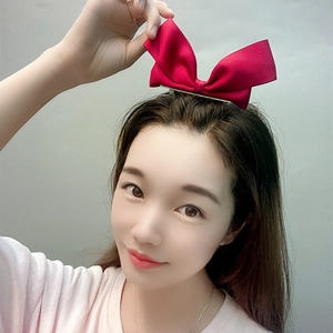 Detailed view of a large red ribbon bow hair clip on a model with premium satin texture
