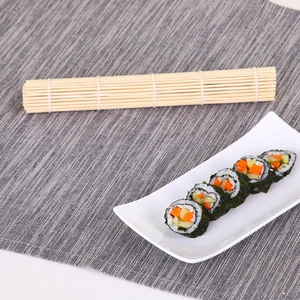 Handcrafted bamboo sushi rolling mat with fresh sushi rolls on a gray textured background