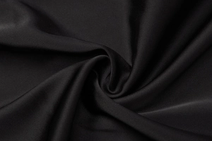 Macro del tessuto nero setoso che mostra la trama delicata e il drappeggio liscio