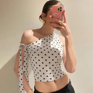Close-up of white polka dot one-shoulder crop top with ribbon tie detail and slim fit