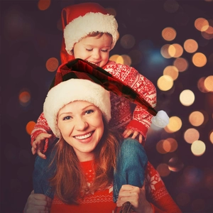 Close-up of mother and child wearing festive red buffalo plaid and classic plush Santa hats