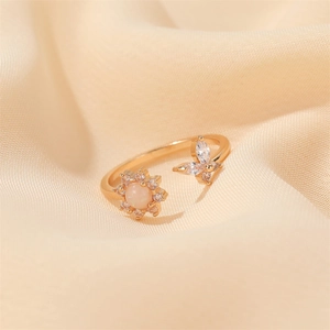 Macro shot of gold-plated open ring featuring an opal sunburst and crystal butterfly detail