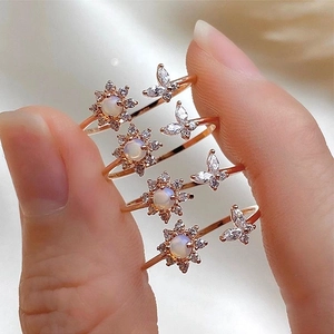 Close-up of four rose gold adjustable rings with opal flowers and zircon butterflies