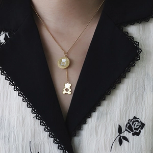 Detail of rose gold Y-necklace with white mother-of-pearl bear pendant on model