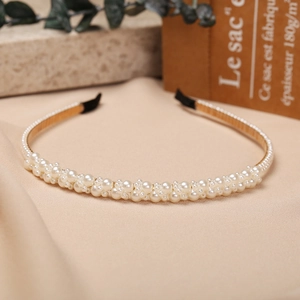 Detailed view of elegant pearl headband with gold metal base on warm fabric background