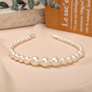 Macro detail of elegant gradient pearl headband with polished finish on silk background