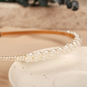 Close-up of elegant pearl headband with multi-size white pearls on a gold wire base