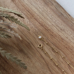 Detailed close-up of a 18K gold-plated satellite chain with a white mini freshwater pearl