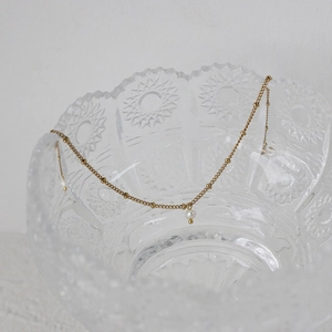 Detail of satellite chain necklace with a small white pearl pendant on glass edge